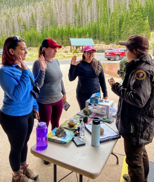 image shows three adult women being sworn in as Junior Rangers at Rocky Mountain National Park. The image does not display irony.