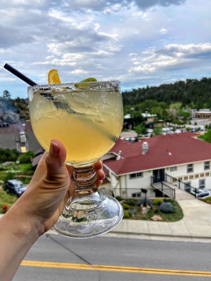 image shows a margarita being held up outside a restaurant at Estes Park, colorado. The margarita looks refreshing.
