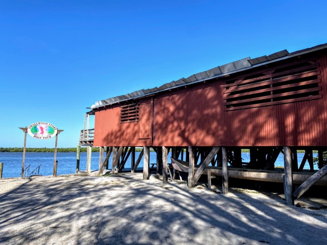 image shows the historic Smallwood store, a red building on stilts in front of the ocean