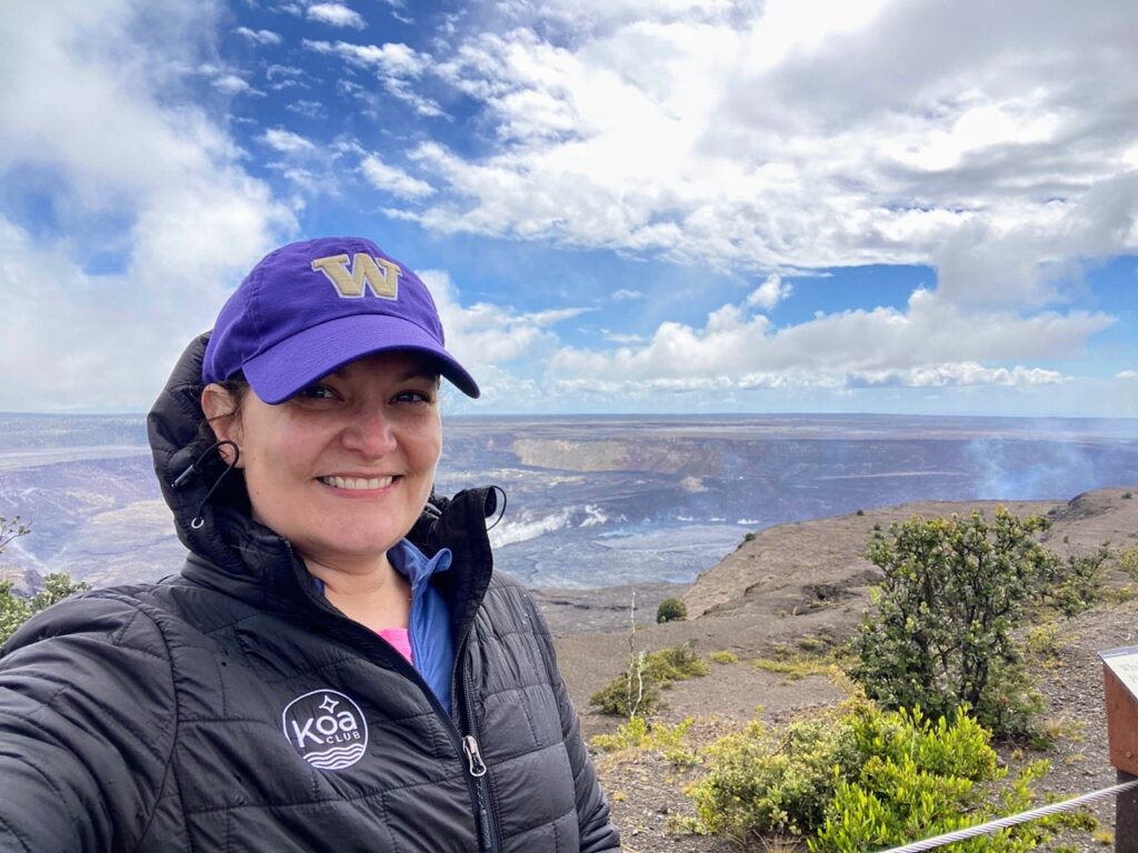 image shows a woman in a UW hat in front of the steam vents of Kilauea crater, part of a five day itinerary focused on national parks on the Big Island of Hawaii