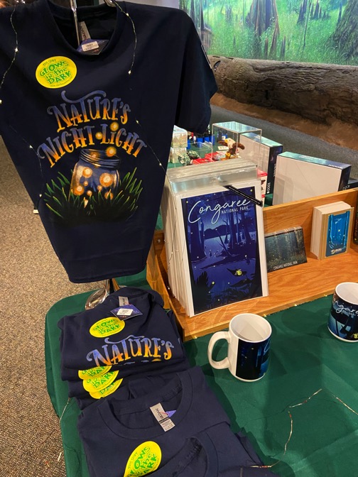 image shows a retail display of firefly festival tshirts, mugs and posters