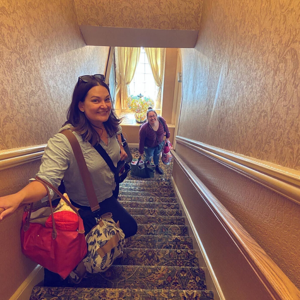 image shows two women laden down with luggage in a hotel stairwell to the third floor