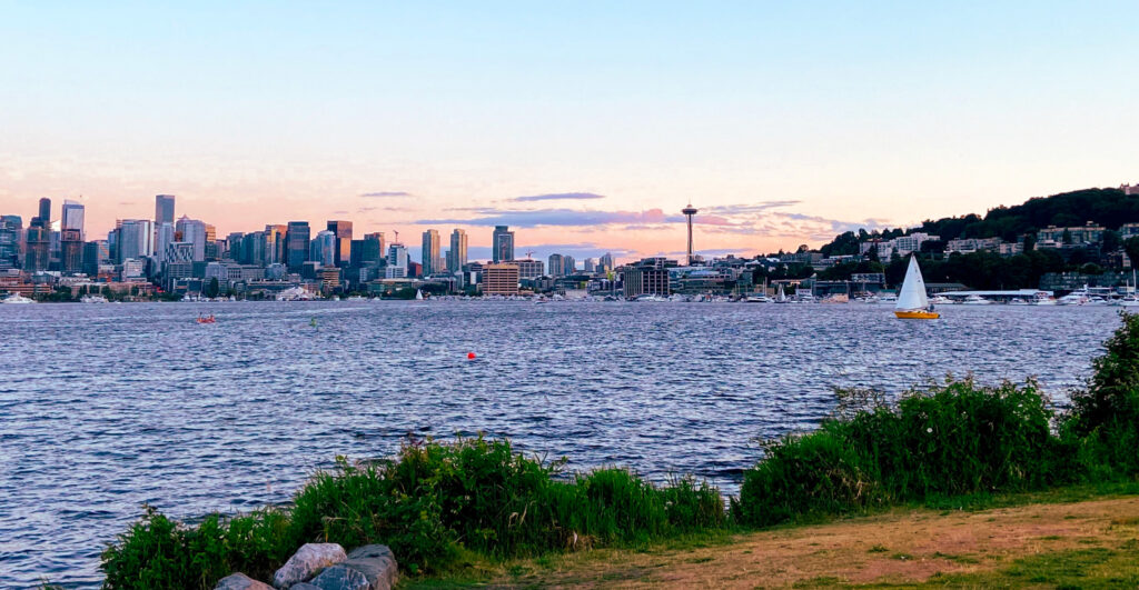 image shows Lake Union and the Seattle skyline behind it in the summer