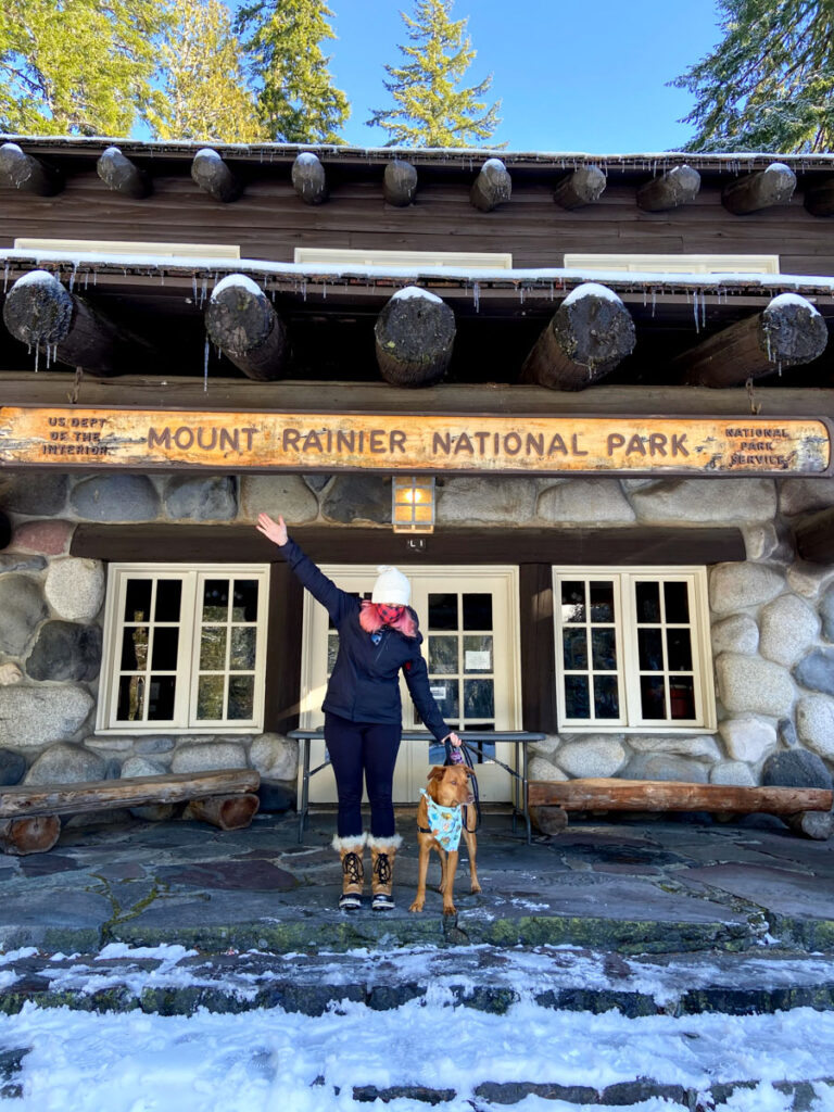 photo shows a woman with pink hair and friendlydog in front of the visitor center at mt rainier national park