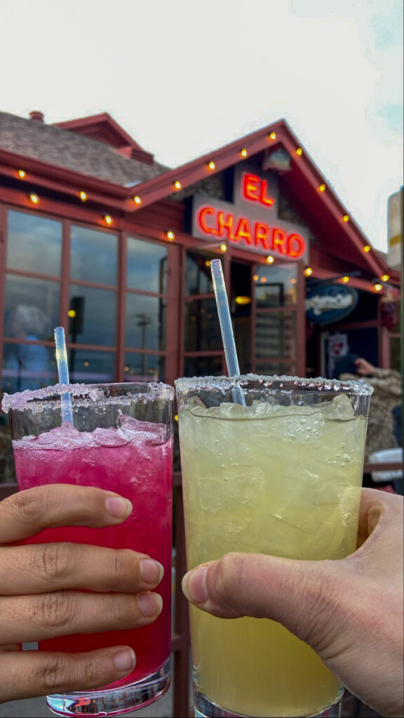 image shows two people cheersing with mararitas in front of a mexican restaurant
