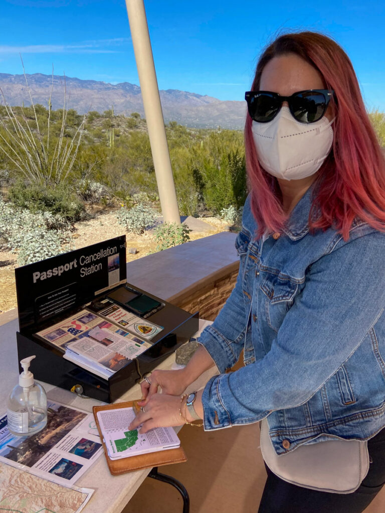 a woman with pink hair getting a passport stamped at Saguaro National Park