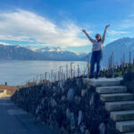 image shows a woman standing on small steps in front of lake geneva in the lavaux region