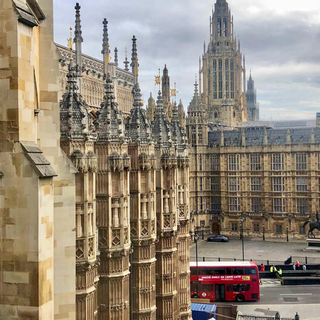 image shows a red London doubledecker bus with Parliament in the background taken from Westminster