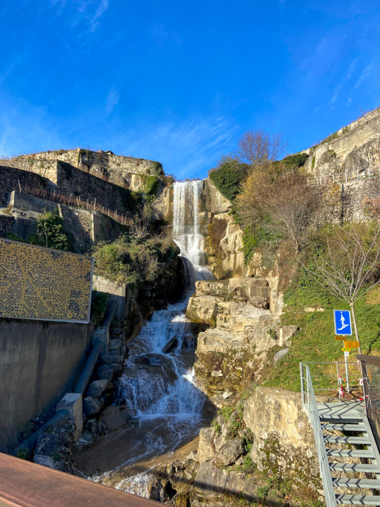 a waterfall decorates the Vinorama building. to the right is a metal staircase to lead to the hiking trails in Lavaux that are open even in winter
