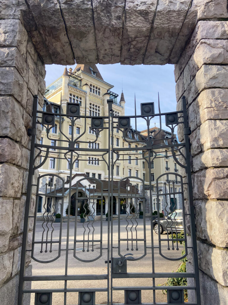 royal savoy hotel, a lush luxury hotel in lausanne, as seen through the iron bars of the front gate