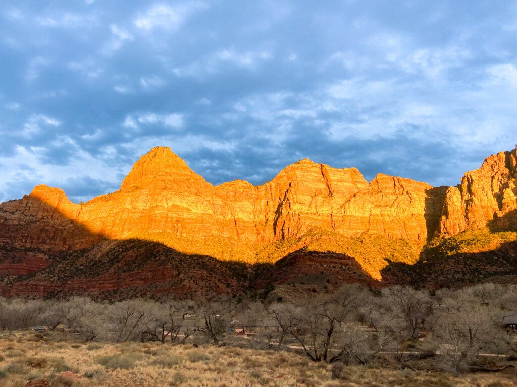 The imposing Zion Canyon walls glow orange in the sunset light.