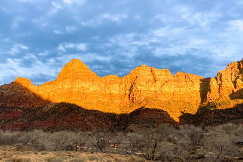 The imposing Zion Canyon walls glow orange in the sunset light.